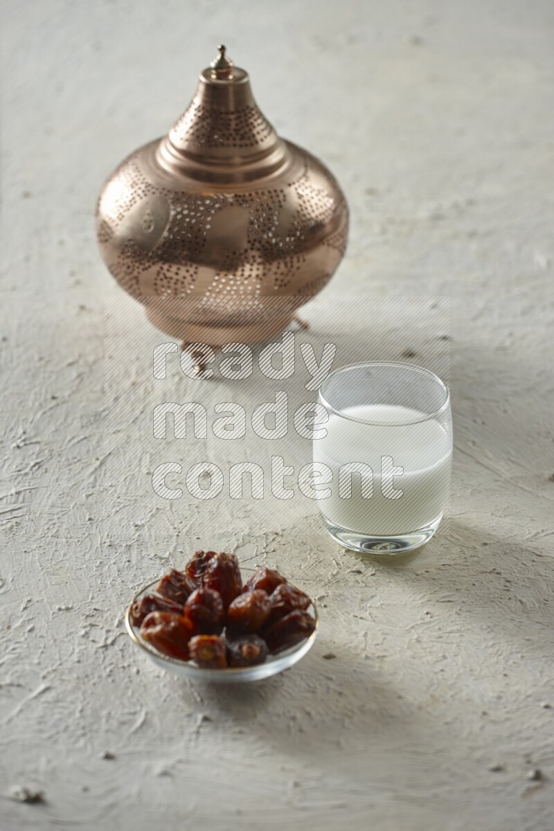 A golden lantern with different drinks, dates, nuts, prayer beads and quran on textured white background