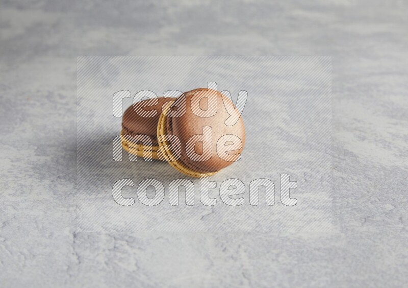 45º Shot of two Yellow and Brown Chai Latte macarons r on white  marble background