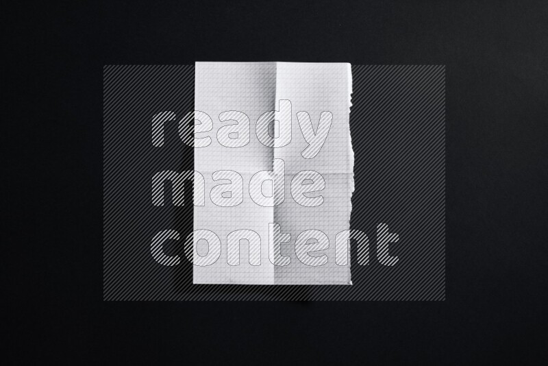 Folded notebook sheet on black background