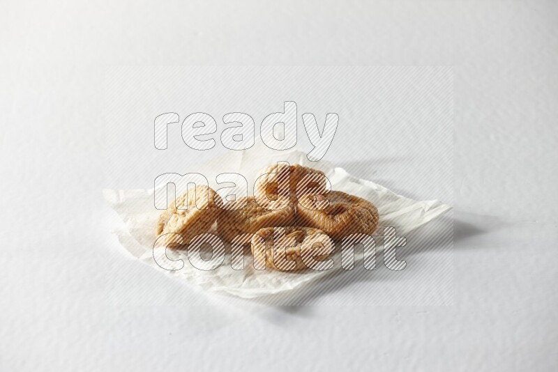 Dried figs on a crumpled piece of paper on a white background in different angles