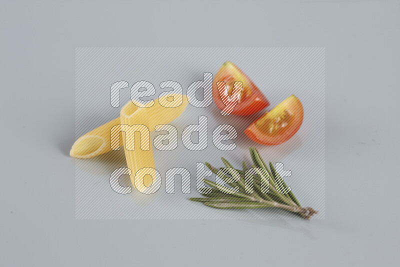 Raw pasta with different ingredients such as cherry tomatoes, garlic, onions, red chilis, black pepper, white pepper, bay laurel leaves, rosemary, cardamom and mushrooms on light blue background