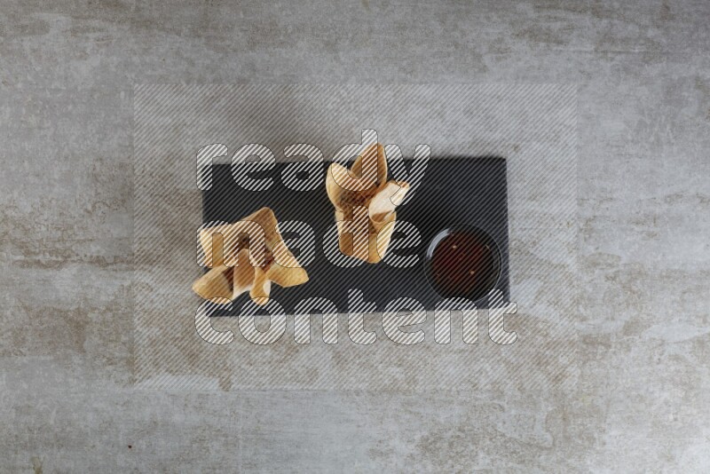 wonton cups with soy sauce ramkin on rectangle slate on grey textured counter top