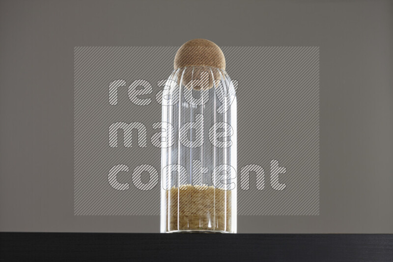Basmati golden rice in a glass jar on black background