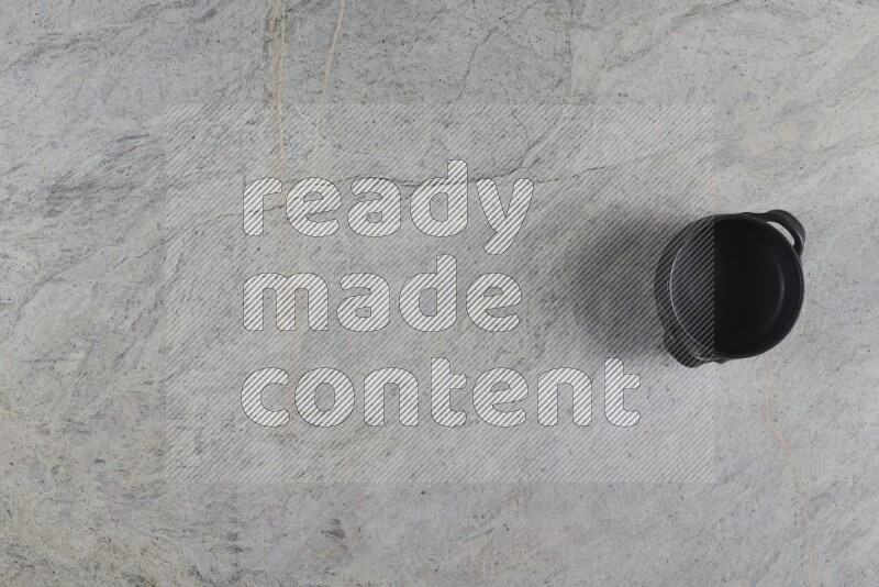 A black pottery bowl on grey marble background