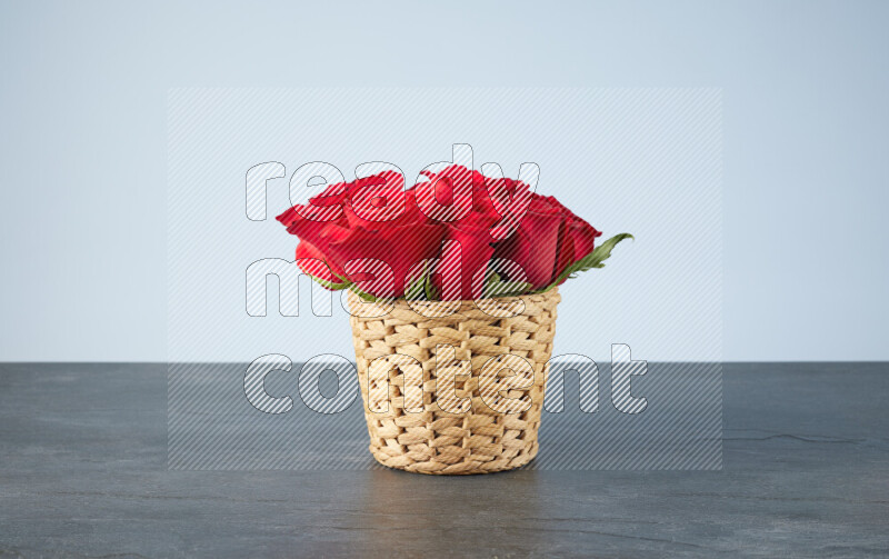 Vibrant red roses in a wicker basket on black marble background