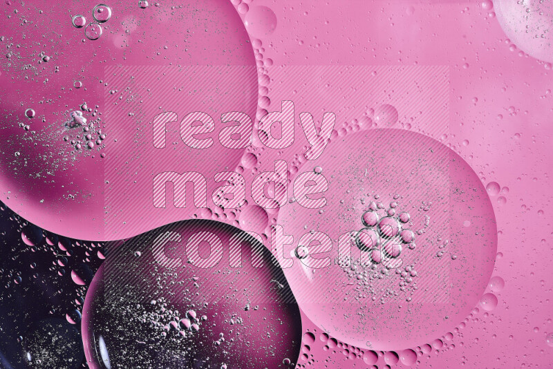 Close-ups of abstract oil bubbles on water surface in shades of black and pink