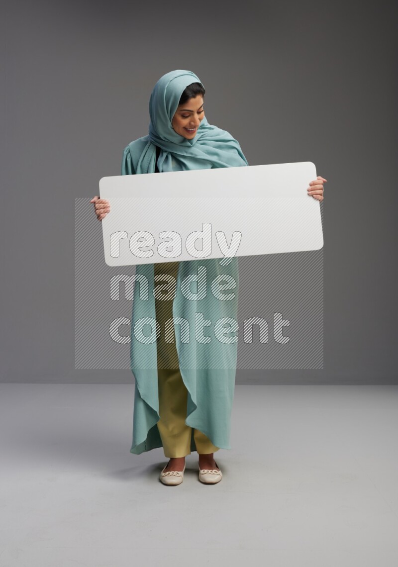 Saudi Woman wearing Abaya standing holding board on Gray background