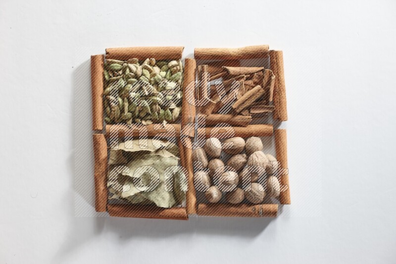 4 squares of cinnamon sticks full of nutmegs, bay laurel leaves, cardamom and cinnamon on white flooring