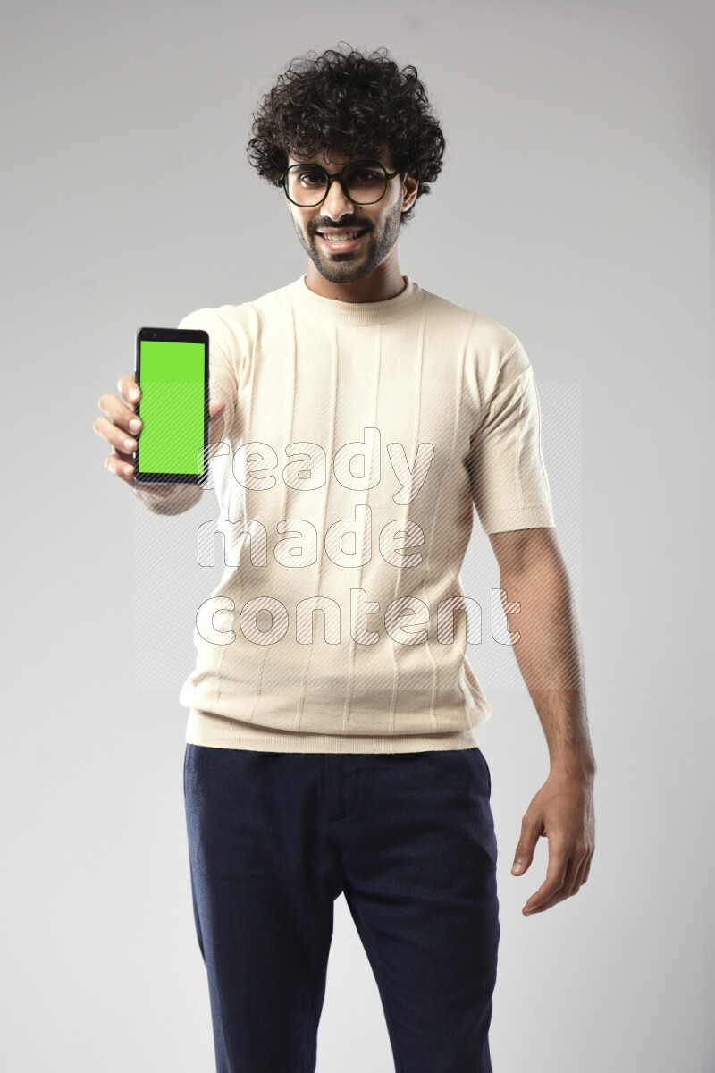 A man wearing casual standing and showing a phone screen on white background