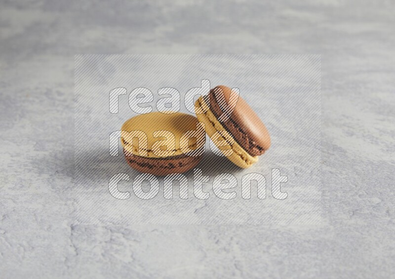45º Shot of two Yellow and Brown Chai Latte macarons r on white  marble background