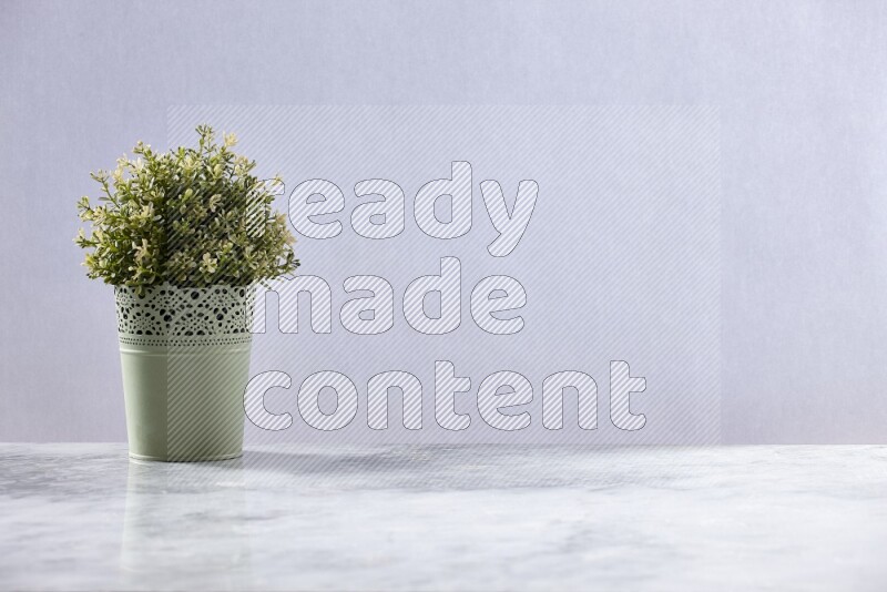 Artificial plant in green decorative pot on grey marble background