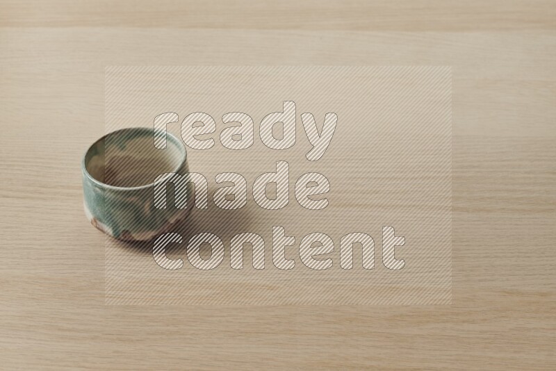 A multicolored pottery bowl on light wooden background