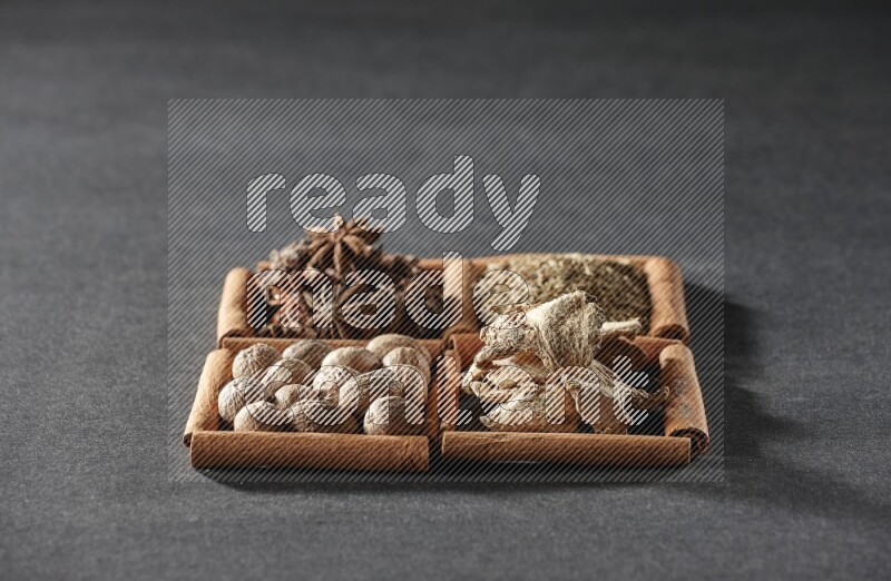 4 squares of cinnamon sticks full of star anise, cumin, dried ginger and nutmegs on black flooring