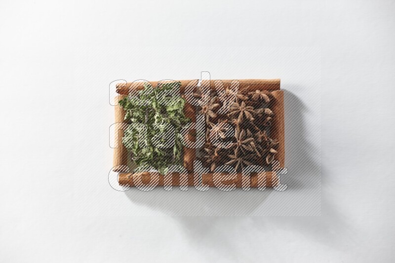 مربعان من أعواد القرفة ممتلئان باليانسون النجمي والنعناع المجفف علي خلفية بيضاء