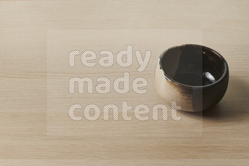 A multicolored pottery bowl on light wooden background