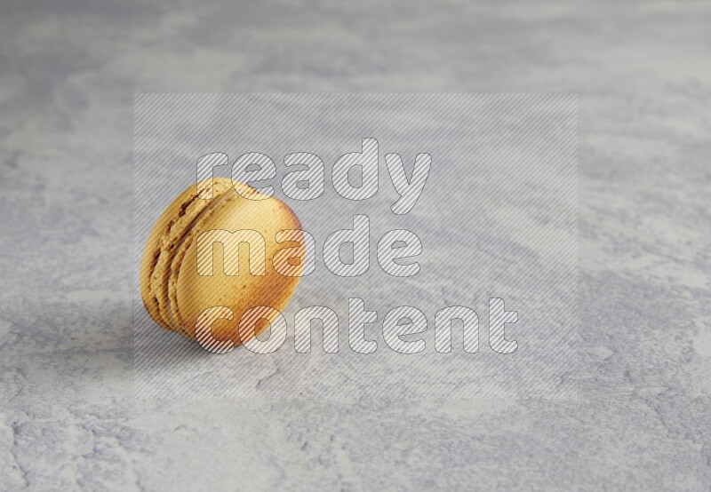 45º Shot of Yellow Crème Brulée macaron on white marble
