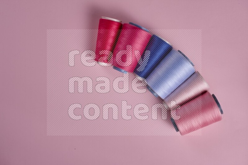 A blue collection of sewing and tailoring tools arranged on a pink background