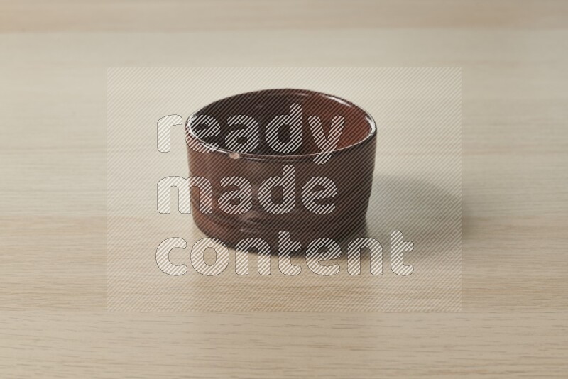 A brown pottery bowl on light wooden background