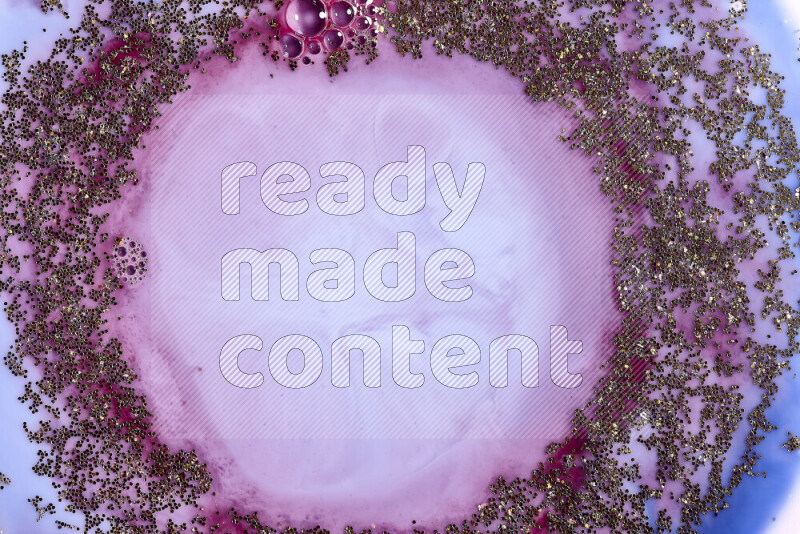 A close-up of sparkling gold glitter scattered on swirling blue and red background