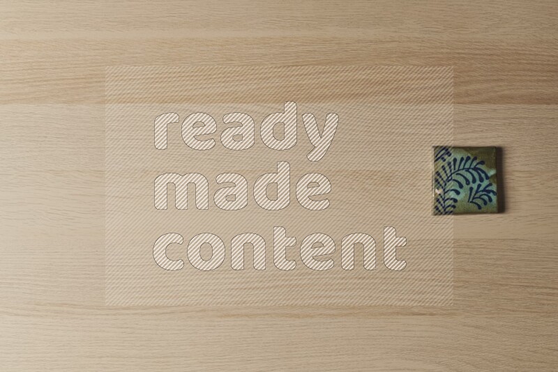 A decorative pottery coaster on light wooden background