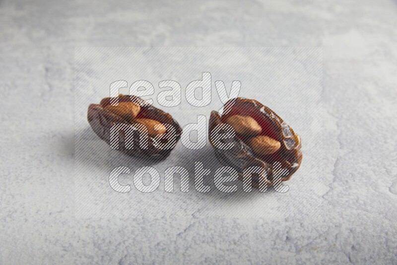 two almond stuffed madjoul dates on a light grey background