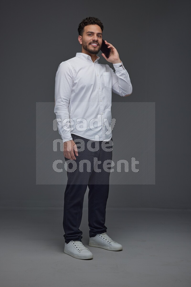 A man wearing smart casual talking in the phone eye level on a gray background