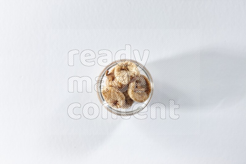 وعاء زجاجي ممتلئ بالتين المجفف على خلفية بيضاء