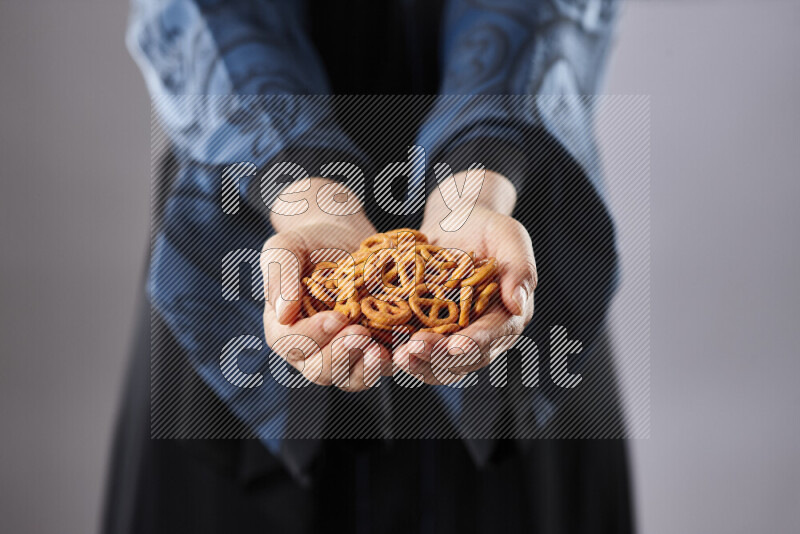 Woman in abaya holding different kinds of snacks in different positions