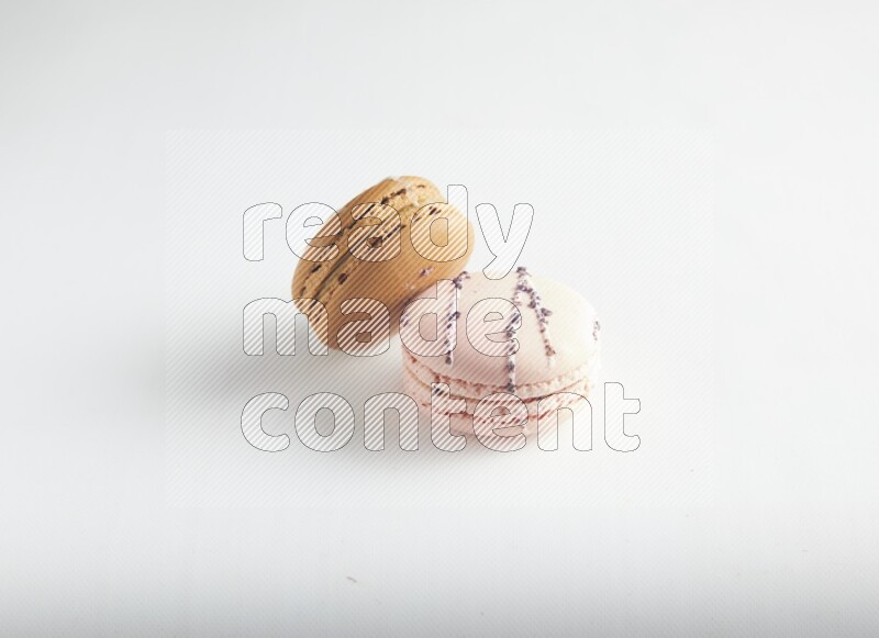 45º Shot of of two assorted Brown Irish Cream, and pink orange blossom macarons on white background