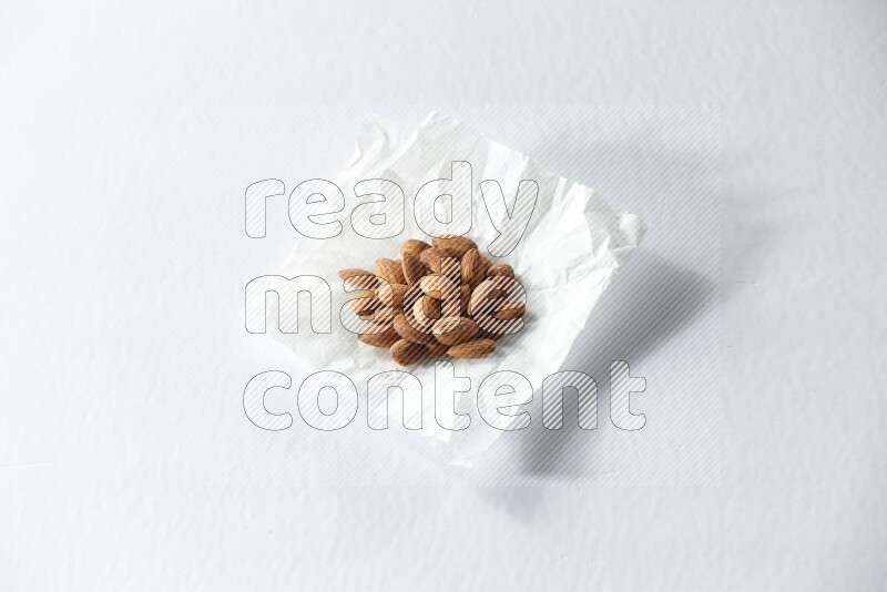 Peeled almonds on a crumpled piece of paper on a white background in different angles