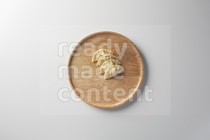Four Sambosas on a wooden round plate on a white background