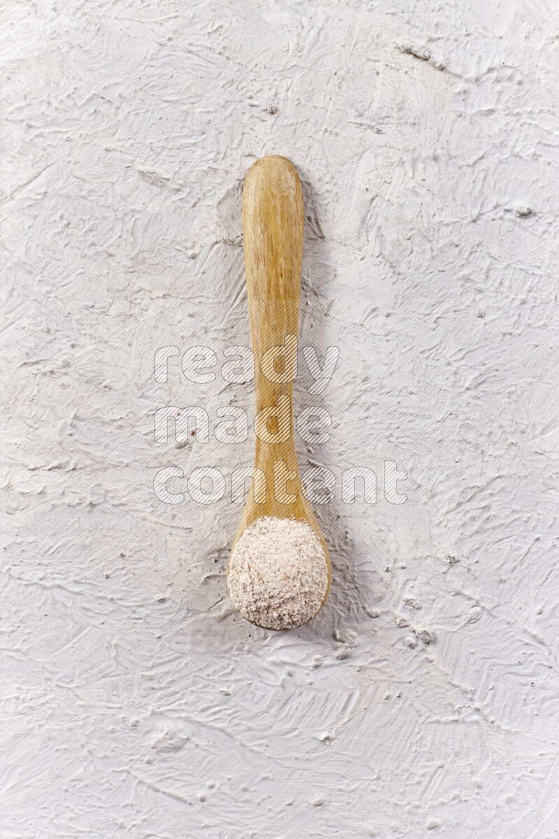 A wooden spoon full of onion powder on white background