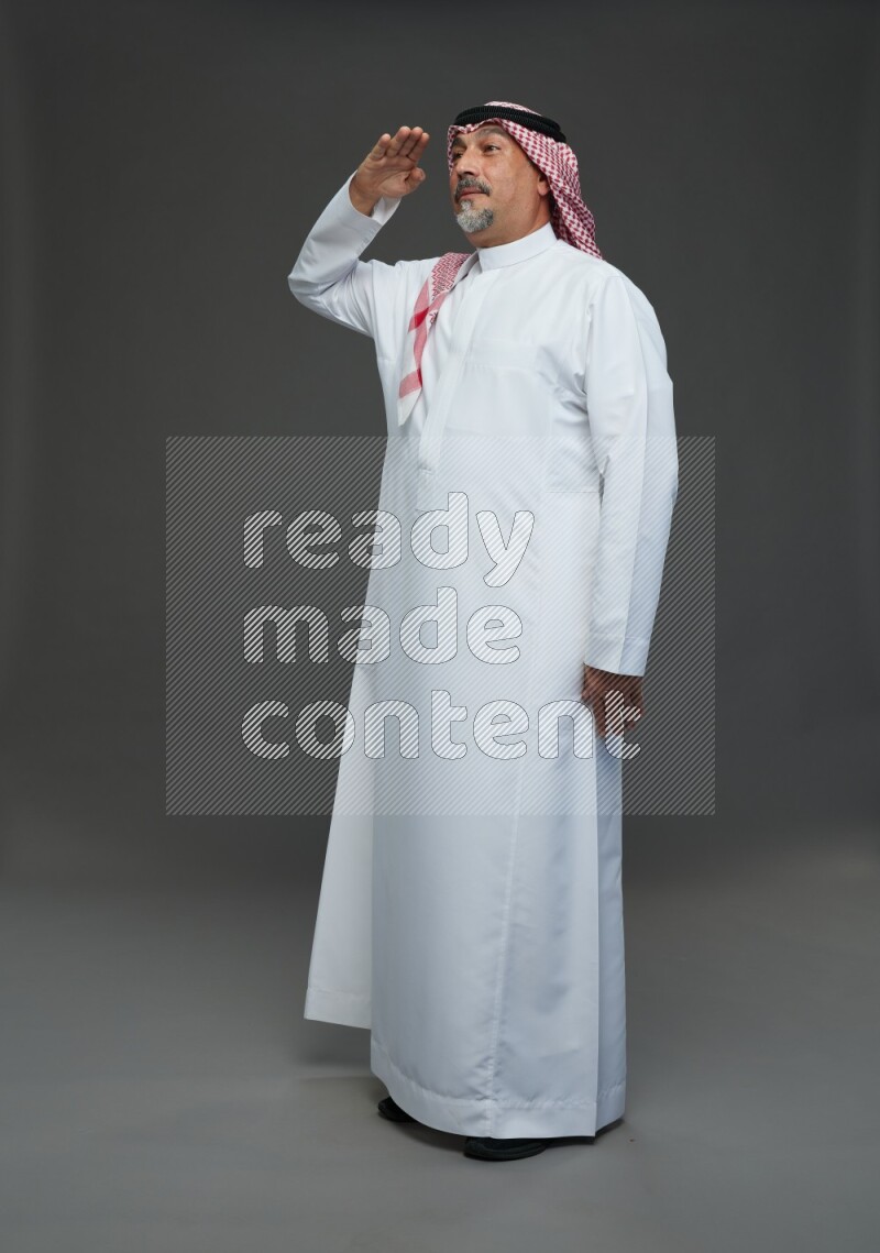 Saudi man with shomag Standing Interacting with the camera on gray background