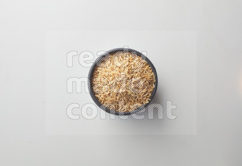 Top-view shot of long grain brown rice in a container on white background