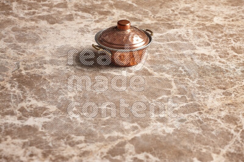 A small copper pot on beige marble background