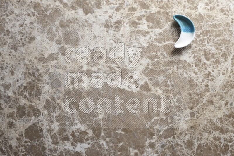 A pottery crescent plate on beige marble background