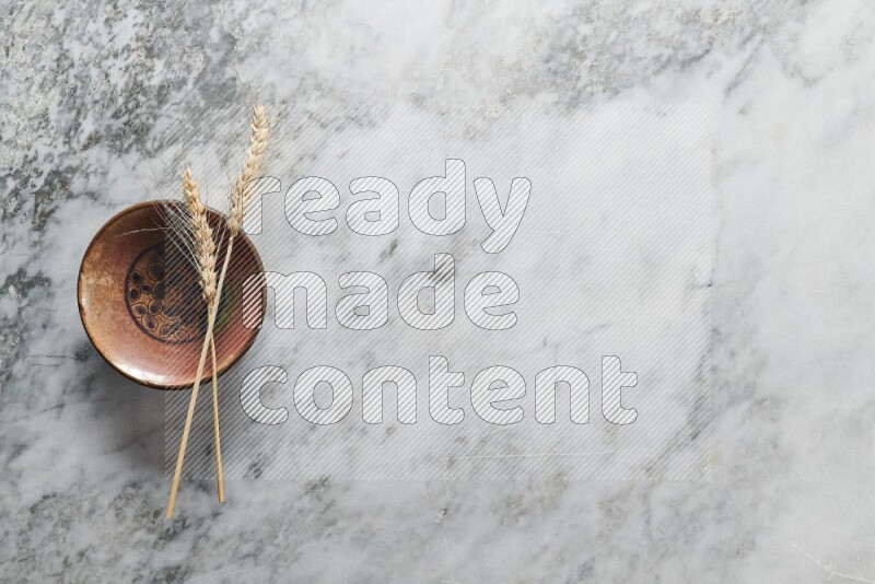 Wheat stalks on decorative pottery plate on grey marble background