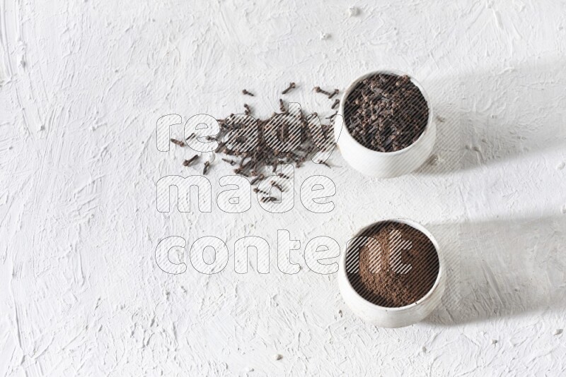 وعاءين من السيراميك بيج اللون، أحدهما مملوء بالقرنفل والآخر مملوء بالبودرة على أرضية بيضاء