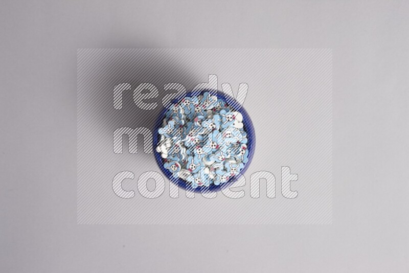 A multicolored pottery bowl full colored buttons on grey background