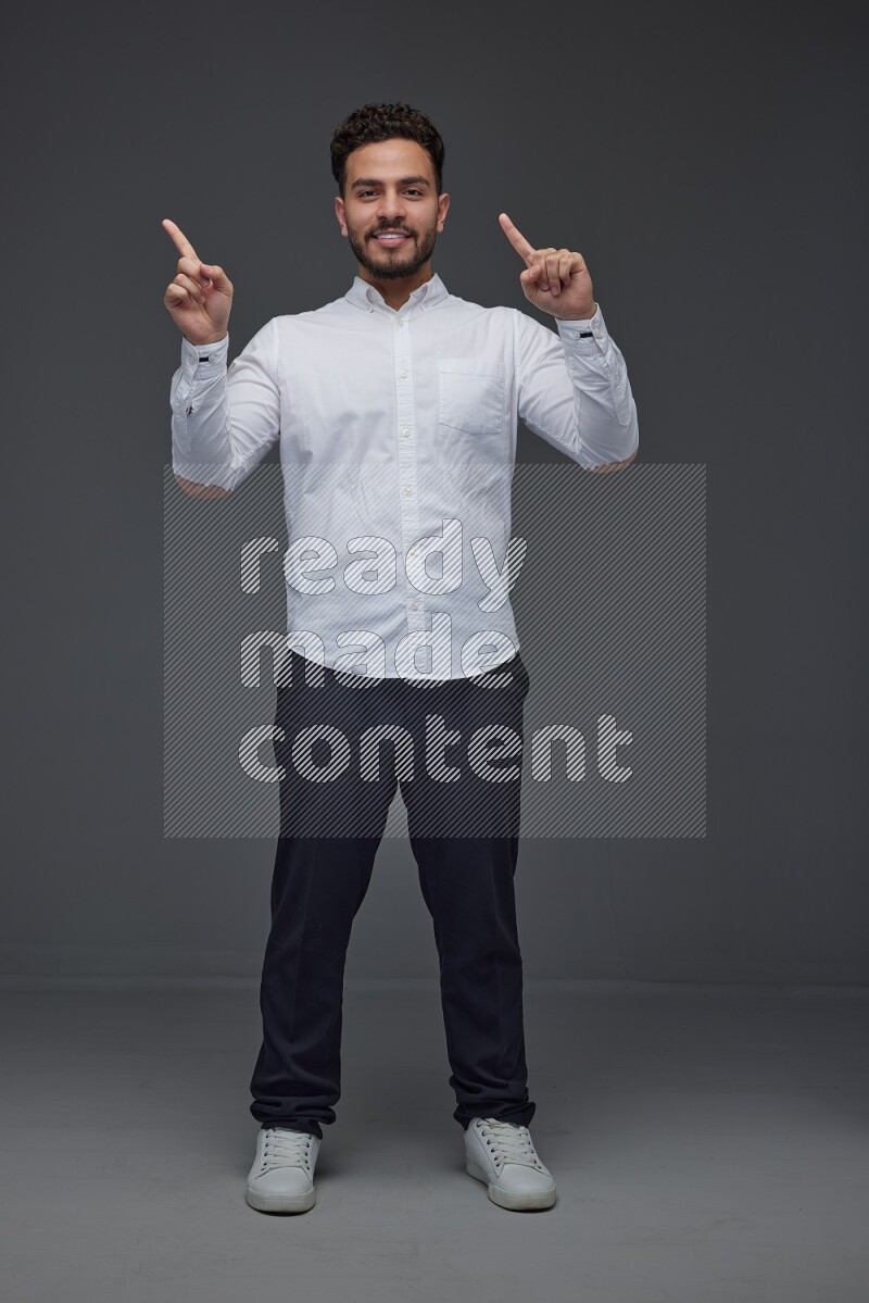 A man wearing smart casual standing and making multi hand gestures eye level on a gray background