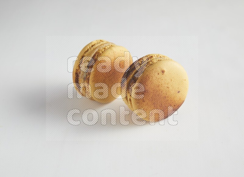 45º Shot of two Yellow Crème Brulée macarons on white background