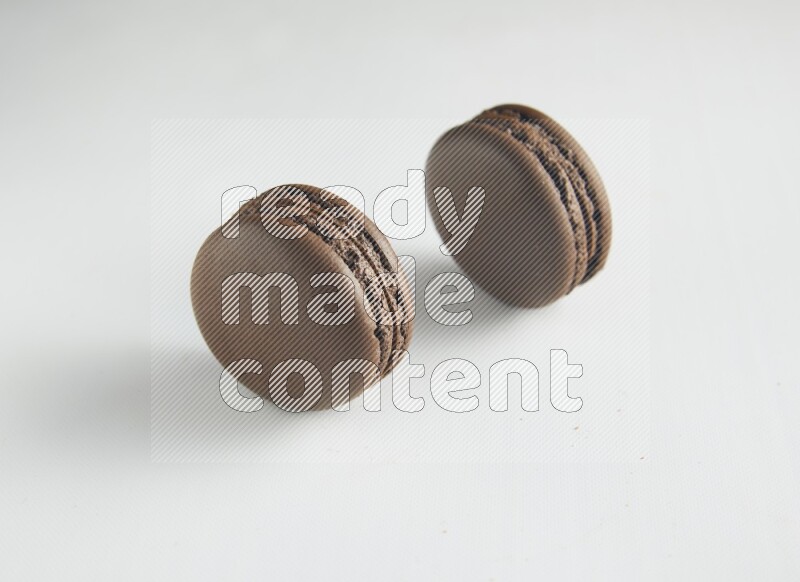 45º Shot of two Brown Dark Chocolate macarons on white background