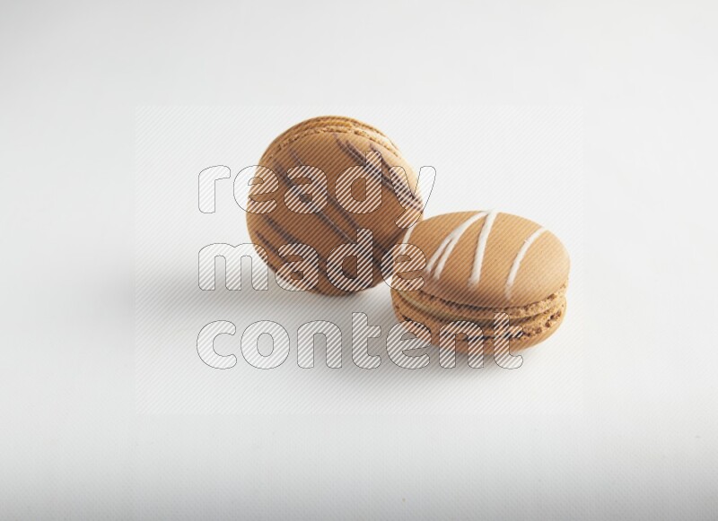 45º Shot of of two assorted Brown Irish Cream, and light brown  Almond Cream macarons on white background