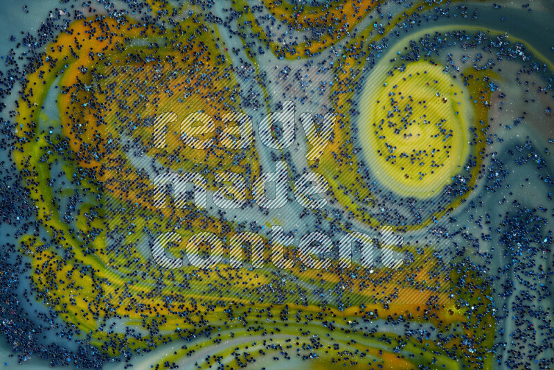 A close-up of sparkling blue glitter scattered on swirling blue and yellow background