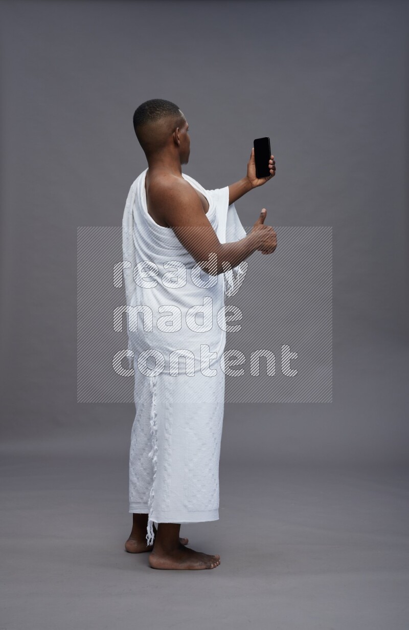 A man wearing Ehram Standing taking selfie on gray background