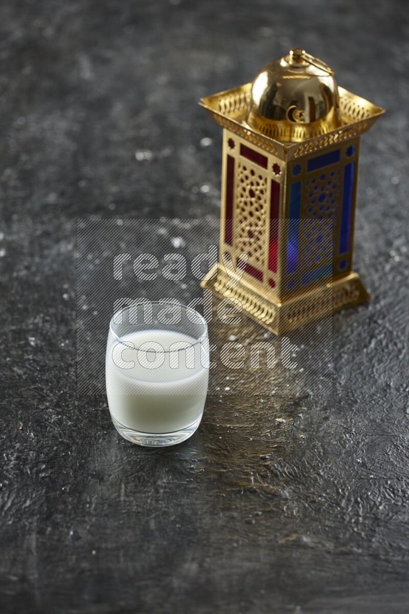 A golden lantern with different drinks, dates, nuts, prayer beads and quran on textured black background