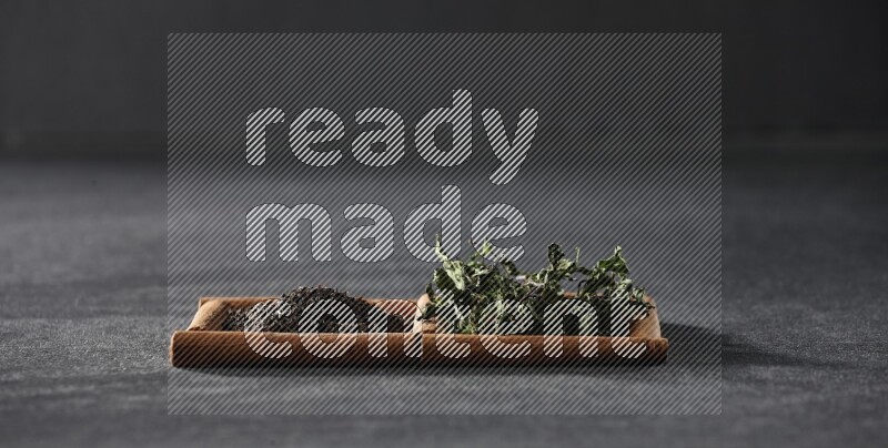 مربعان من أعواد القرفة ممتلئان بالشاي والنعناع المجفف علي خلفية سوداء