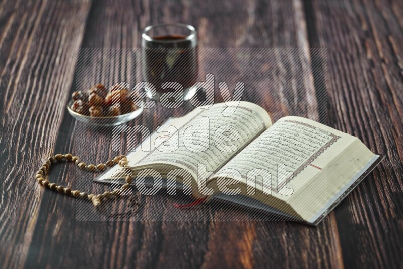 Quran with dates, prayer beads and different drinks all placed on wooden background