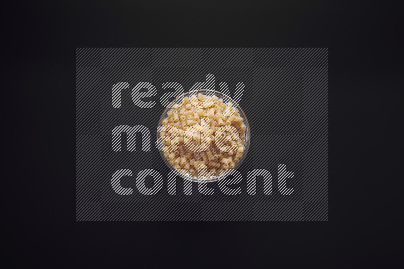 Small rings pasta in a glass bowl on black background