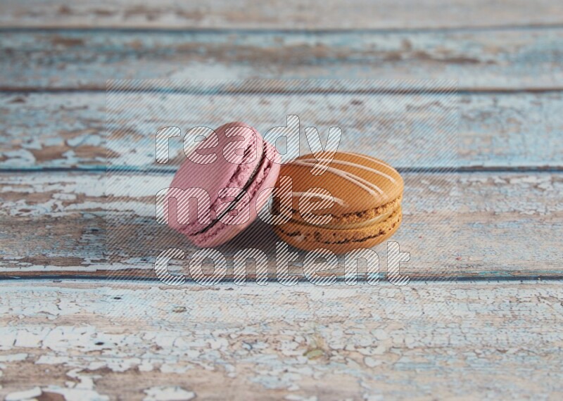 45º Shot of of two assorted Brown Irish Cream, and Purple Strawberry macarons  on light blue background